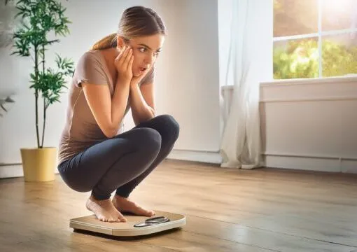 体重計にのって驚く女性